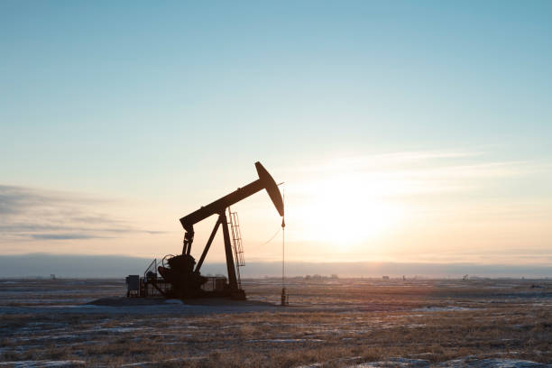 North American  Oil Single pump jack producing oil, sun rising. Image taken from a tripod. oil stock pictures, royalty-free photos & images