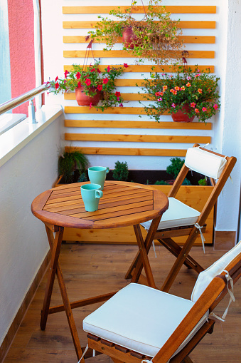 Beautiful modern balcony with wooden table, two chairs and two coffee cups waiting for a couple to relax