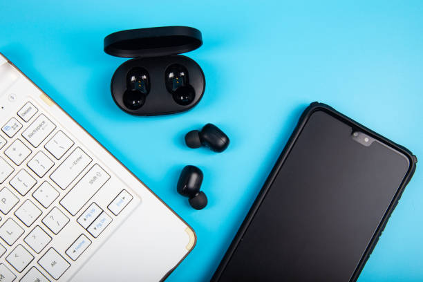 istock White keyboard, Smartphone with Wireless bluetooth headphones isolated on blue background 1220237107