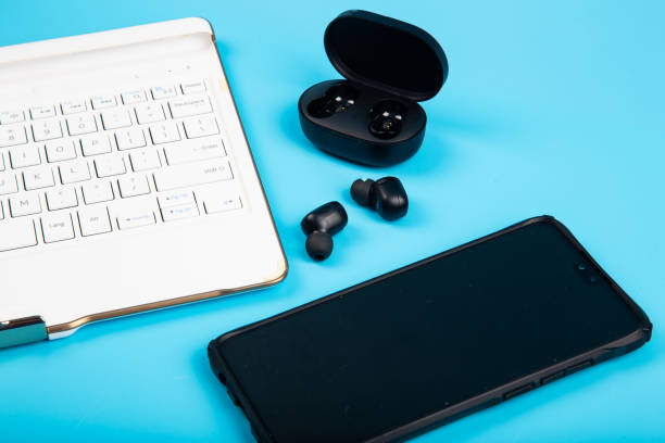 istock White keyboard, Smartphone with Wireless bluetooth headphones isolated on blue background 1220237654