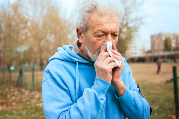 istock Elderly man blowing nose with handkerchief 1220237818