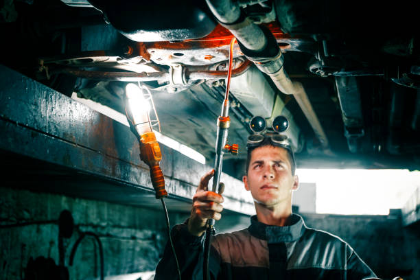istock Mechanic welding car bottom in car repair pit 1220238078