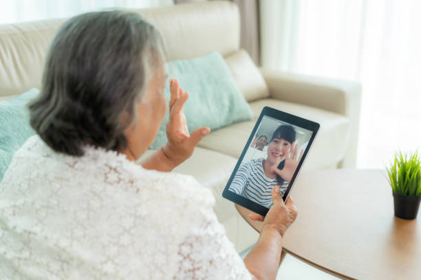 Asian elderly woman virtual happy hour meeting and talking online together with her daughter in video conference with tablet for a online meeting in video call for social distancing. Asian elderly woman virtual happy hour meeting and talking online together with her daughter in video conference with tablet for a online meeting in video call for social distancing. videocall elderly asian parents stock pictures, royalty-free photos & images