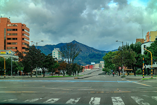 Bogota, Colombia - April 11, 2020: These are the eastbound carriageways of the usually busy Calle 100 or 100 Street, where they meet Carrera 11 in the Colombian Capital city of Bogota. There usually is heavy vehicular traffic in the area, at this time of the day. Today, it is deserted due to the Coronavirus lockdown declared by the Government in the Country. Only people with valid reasons are allowed to step outside. In the middle of the image is the landmark bridge on Calle 100 over Cra 9 and 30. In the far background are the Eastern Hills of the City; the altitude at street level is about 8500 feet above mean sea level. Note to Inspector: All logos and signs have been removed. 'Vendo' in Spanish translates to, \