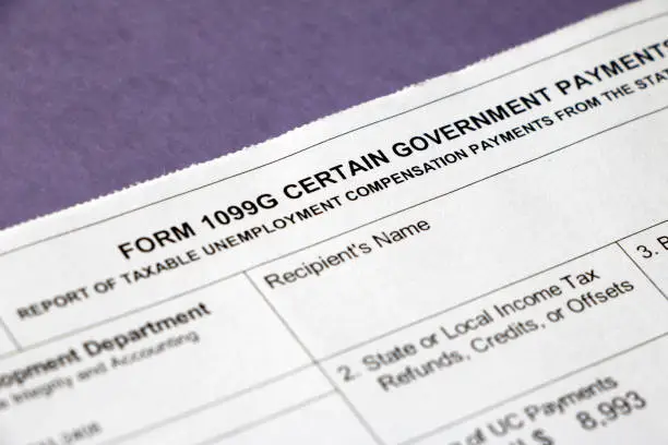 Closeup of the top of a tax Form 1099G Certain Government Payments - Taxable Unemployment Compensation Payments with blueish/purple background.