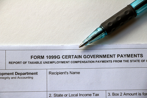 Closeup of the top of a tax Form 1099G Certain Government Payments - Taxable Unemployment Compensation Payments with pen lying on top.