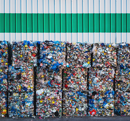 Large bundles of plastic bags, cans and milk containers await processing at a recycling center.