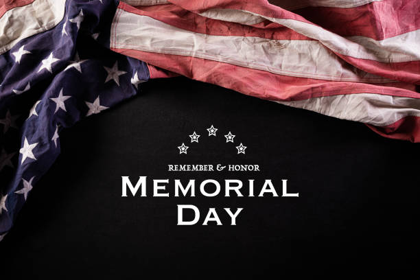 istock Happy Memorial Day. American flags with the text REMEMBER & HONOR against a blackboard background. May 25. 1220253308