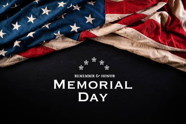 istock Happy Memorial Day. American flags with the text REMEMBER & HONOR against a blackboard background. May 25. 1220253310