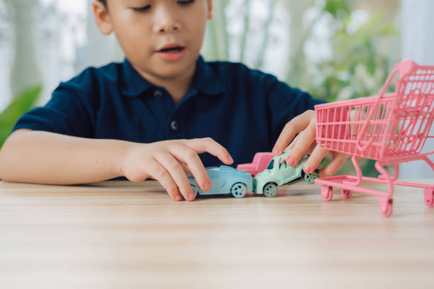 School boy playing with toy car on a table at home.