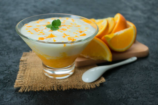 istock Refreshing yogurt dessert with orange smoothie on a black background. 1220259285
