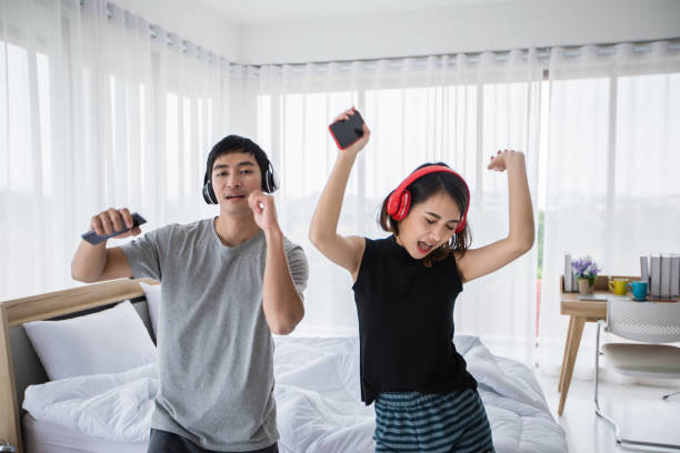 the couple put on their headphones and listened to music on their mobile phones on the couch and they were dancing happy in the house for social distance and self responsibility concept - sex and reproduction audio imagens e fotografias de stock