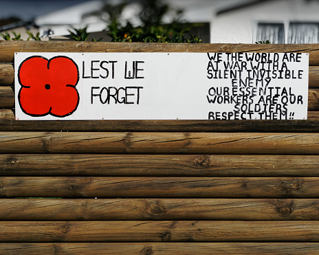 Motueka, Tasman/New Zealand - April 22, 2020: Hand painted sign with poppy and text: Lest we forget. We the world are at war with a silent invisible enemy. Our essential workers are our soldiers, respect them!