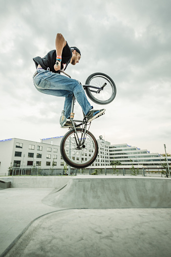 Bmx rider jumping over a ramp in a skatepark.