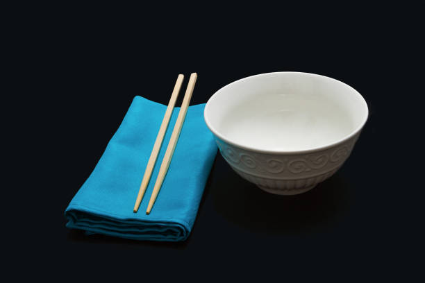 Chopsticks on a blue napkin next to a white empty rice bowl