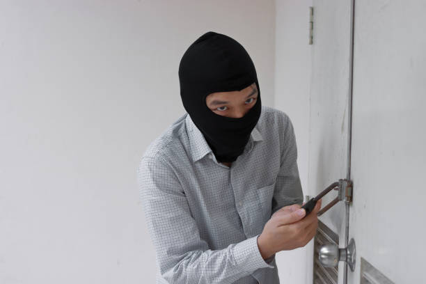 istock Masked thief in black balaclava trying to break into house 1220267514