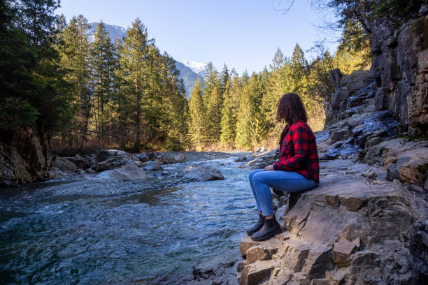 Girl in Canadian Nature Girl Sitting by the river in the Canadian Mountain Landscape during a sunny winter day. Taken in Golden Ears Provincial Park, near Vancouver, British Columbia, Canada. alouette lake stock pictures, royalty-free photos & images