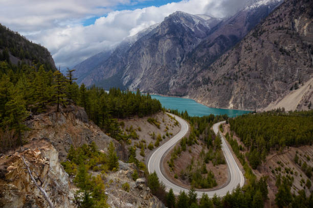 Scenic Road in the Canadian Mountain Landscape Aerial View of a Scenic Road in the Canadian Mountain Landscape during a cloudy springtime. Taken between Pemberton and Lillooet, BC, Canada. pemberton bc stock pictures, royalty-free photos & images