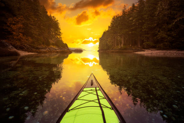 Kayaking on an inflatable kayak in the peaceful ocean by rocky islands near Port Hardy, Vancouver Island, British Columbia, Canada. Sunset or Sunrise Sky Replacement Composite. Concept: Adventure