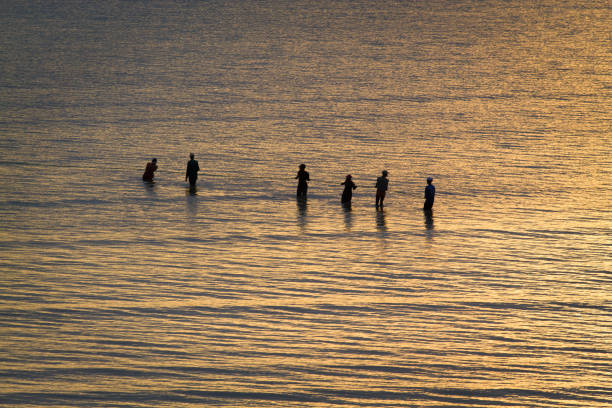 Tanzanian fishermen fishing pulling with net at sunset in the Indian Ocean at the beach of Dar es Salam, Tanzania in Africa.