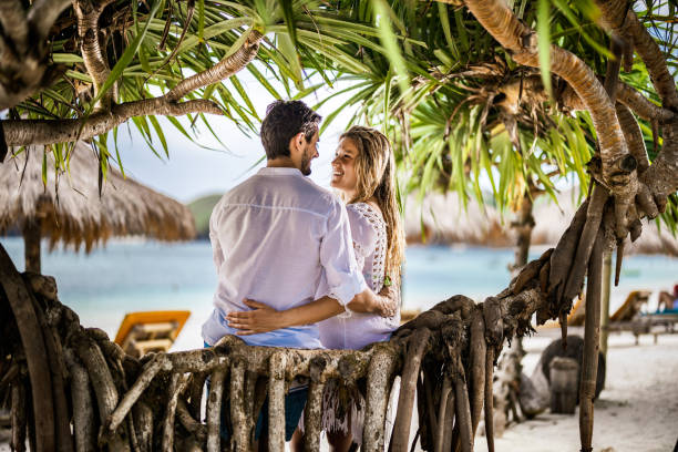 istock Young happy couple talking under tropical tree on the beach. 1220272259