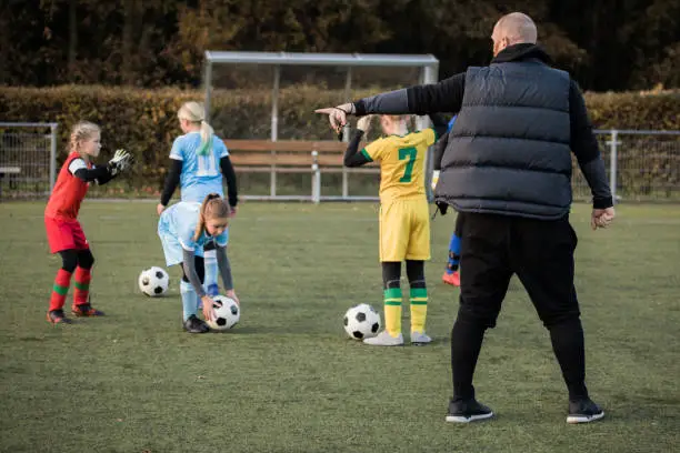 Photo of Soccer father coaching football daughter's team during a training session