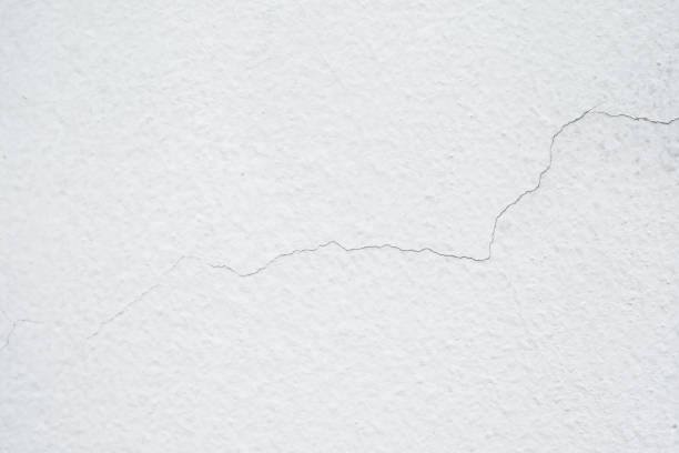 istock Wall with cracked white paint, texture cement large crack for background 1220274576