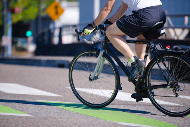 el hombre monta una bicicleta cruzando una calle de la ciudad prefiriendo un estilo de vida activo - racing bicycle fotografías e imágenes de stock