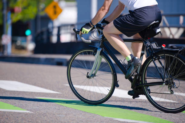 l’homme monte un vélo traversant une rue de ville préférant un mode de vie actif - wheel training sports training bicycle photos et images de collection