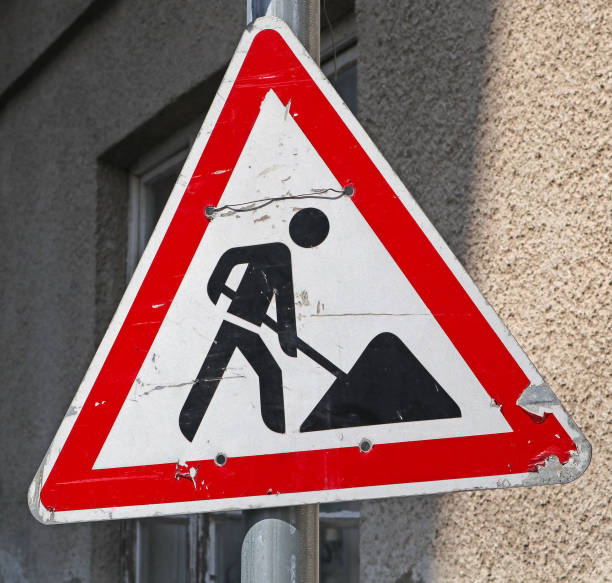 istock Road works road sign next to a building 1220280824