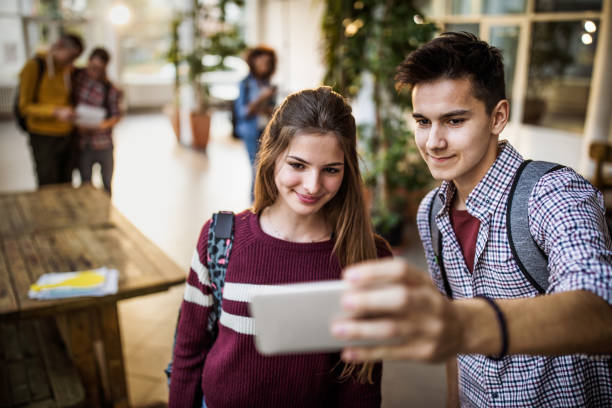 istock Happy high school couple taking a selfie with cell phone. 1220281643