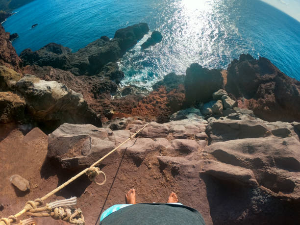 istock First person perspective shot from a Climber Looking down  climbing a rock wall at the edge of a cliff at the shore in Maui, Hawaii. Endless Ocean. View of climber legs. The rope was unsecured. wide lens. 1220283225
