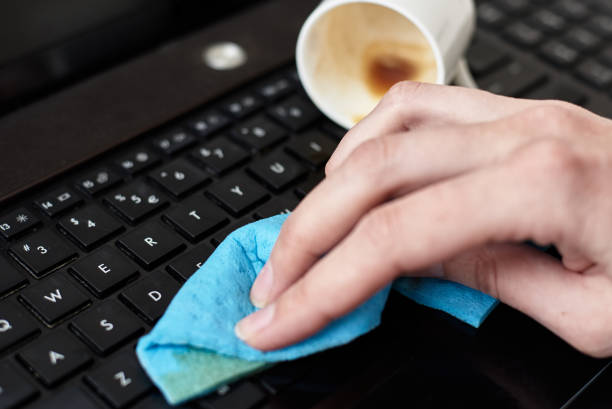istock Hand cleans spilled coffee on laptop keyboard with a rag 1220284149