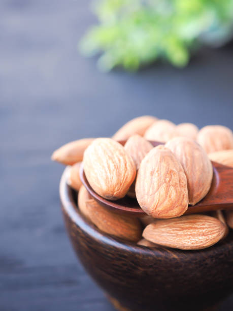 istock Almonds seeds in wooden bowl on black background. 1220284632