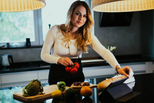 istock Woman making vegetable meal and reading recipe on digital tablet 1220285989