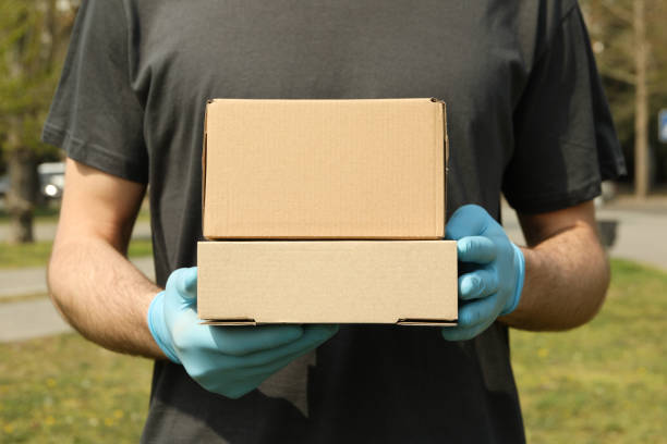 istock Delivery man in gloves holds blank boxes, space for text 1220286171