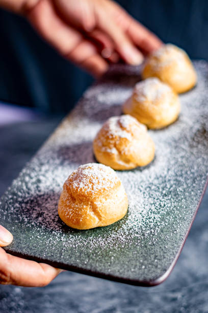istock Eclair, choux filled vanilla custard cream and dusted with icing,  dessert on a plate with copy space 1220287199