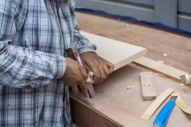 istock Using sandpaper scrub plank wood for making table, furniture 1220287489