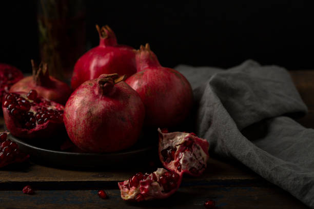 istock Ripe pomegranates on dark moody table 1220288236