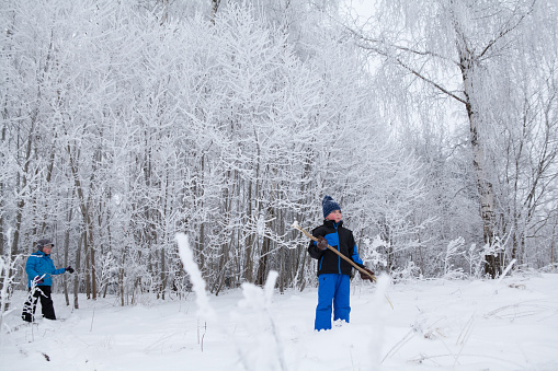 January 14, 2013 - Vilnius, Lithuania: boy standing in deep snow next to bushes covered with frost while his brother follows him - winter playing and games wearing warm clothing