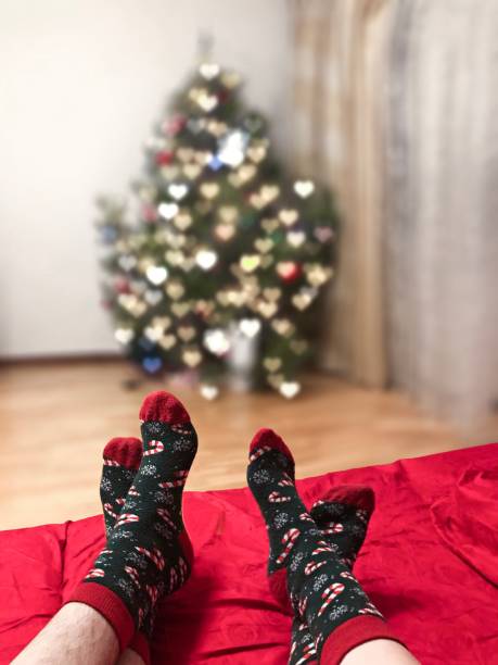 istock Two pairs of feet in Christmas socks near Xmas tree 1220298564