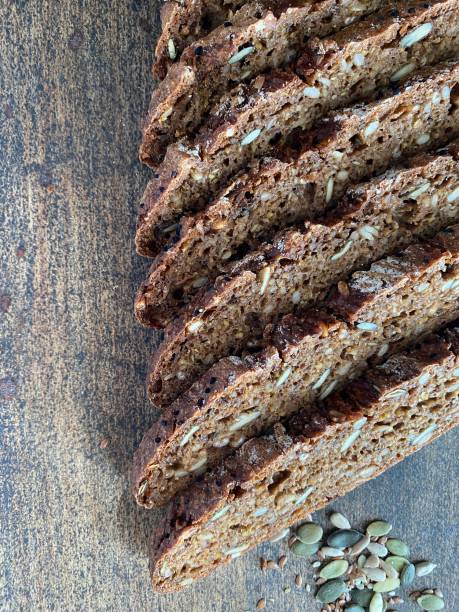 Slices of homemade rye malt dark bread on a rye sourdough with whole rye grains, sunflower seeds, flax, black caraway seeds, sesame seeds, spelled on a dark rustic background. Healthy eating concept. Copy spice rebanadas de pan oscuro de malta de centeno casero sobre una masa fermentada de centeno con granos de centeno entero, semillas de girasol, lino, semillas de caraway negro, semillas de sésamo, deletreados sobre un fondo rústico oscuro. concepto de aliment