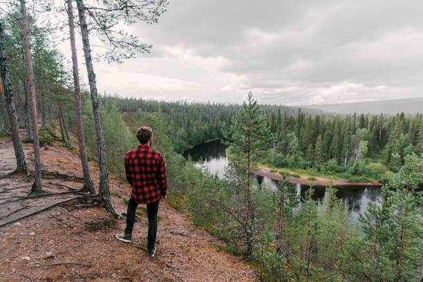 Young Caucasian man walking in the forest near the river in Finland