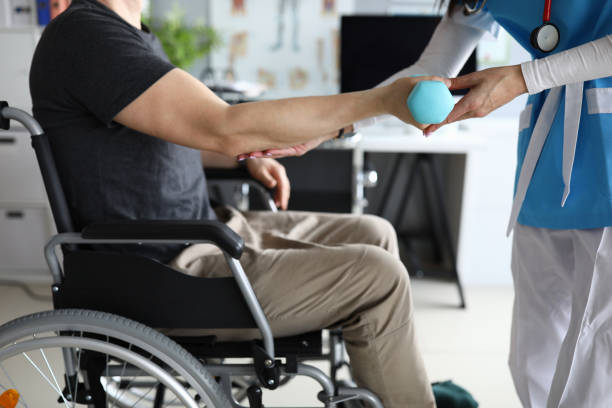 Female nurse helps lift dumbbell to disabled patient rehabilitation therapy Female nurse helps lift dumbbell to disabled patient rehabilitation therapy concept. Process of recovering patients after severe injuries atrophy photos stock pictures, royalty-free photos & images