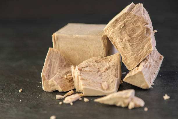 istock cube of fresh yeast whole and crumbled on a black background 1220303084