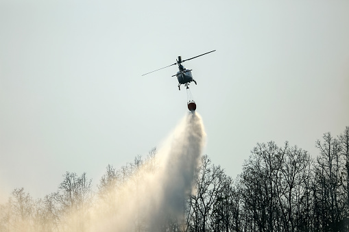 Helicopter dropping water on forest fireHelicopter dumping water on forest fire