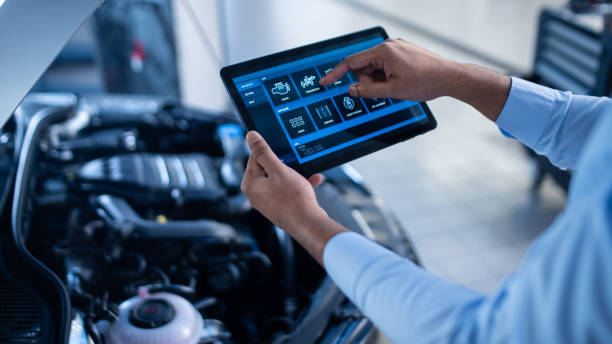 istock Car Service Manager or Mechanic Uses a Tablet Computer with a Futuristic Interactive Diagnostics Software. Specialist Inspecting the Vehicle in Order to Find Broken Components In the Engine Bay. 1220304826
