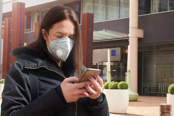 istock Woman in mask texting on way to work 1220304842