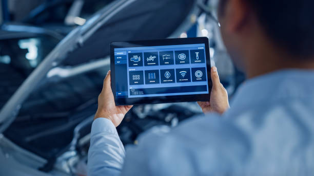 istock Car Service Manager or Mechanic Uses a Tablet Computer with a Futuristic Interactive Diagnostics Software. Specialist Inspecting the Vehicle in Order to Find Broken Components In the Engine Bay. 1220305482