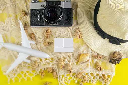 Summer concept. Travel accessories: a straw hat, a camera, a rope, plane, shells and wood cubes.